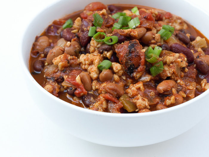 A bowl of tempeh chili with beans and chives on top