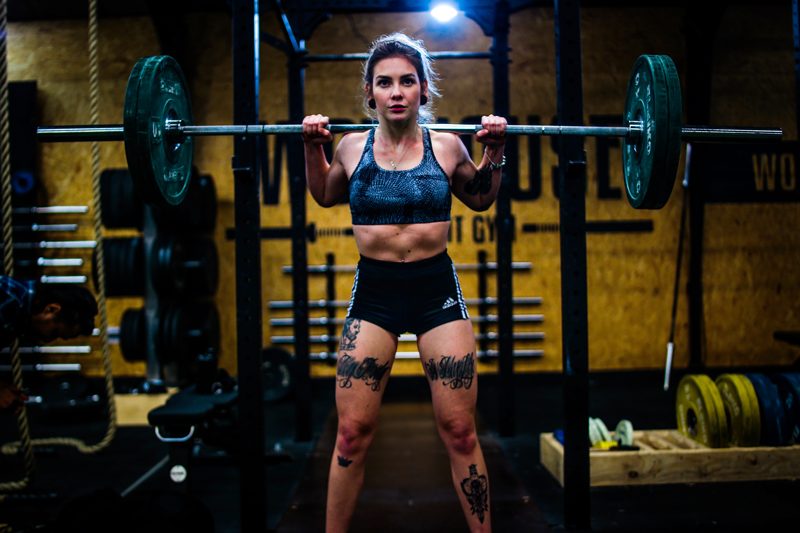 Strong female vegan athlete building muscle by using barbell and following vegan muscle building diet plan